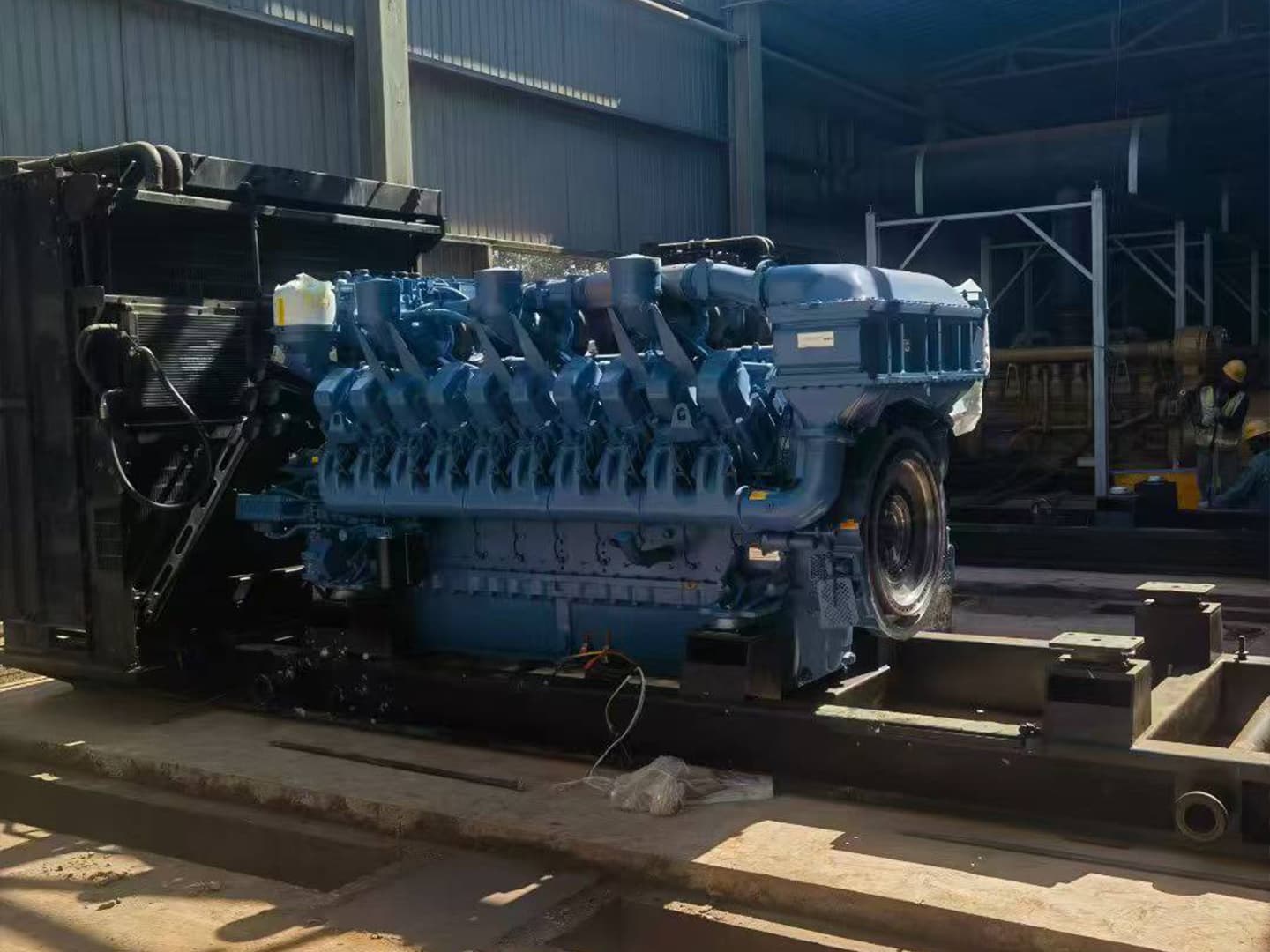 A blue MTU engine being positioned on the base frame inside the workshop